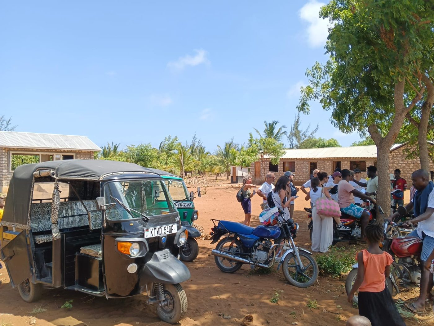 Tuk tuks and visitors gathered at a local village stop near Watamu